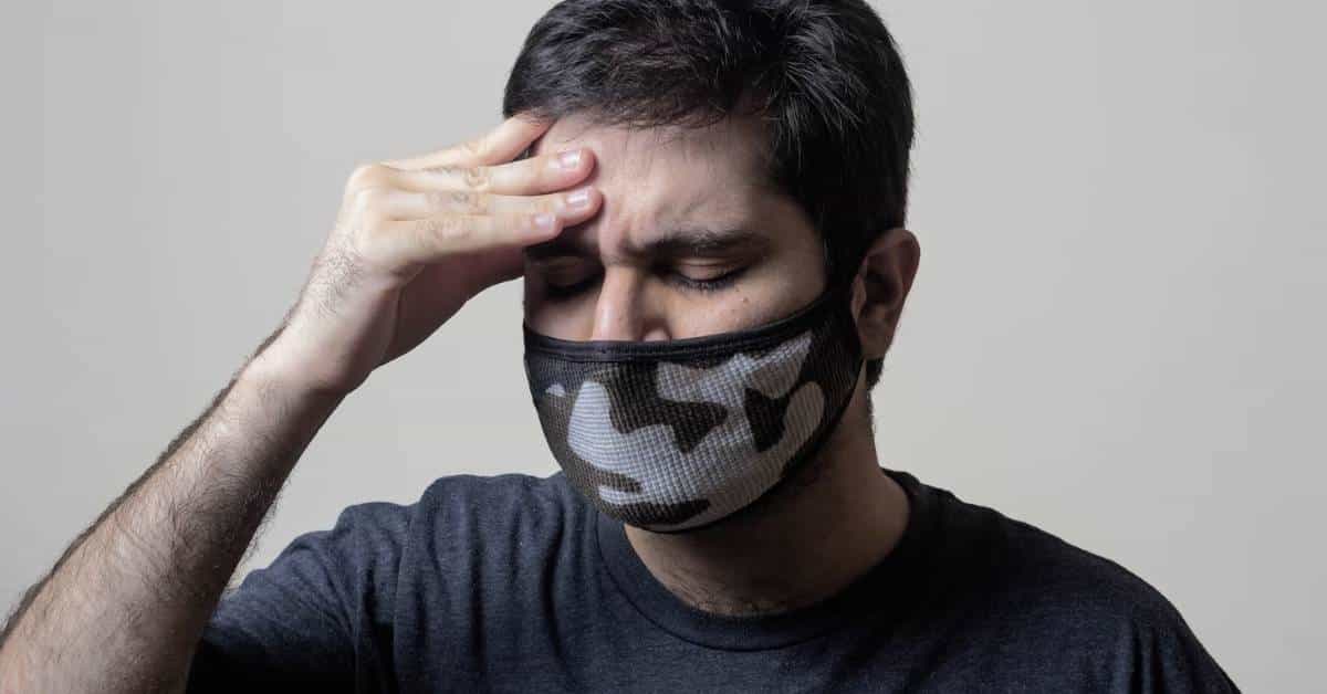 A masked man experiencing headaches due to allergy