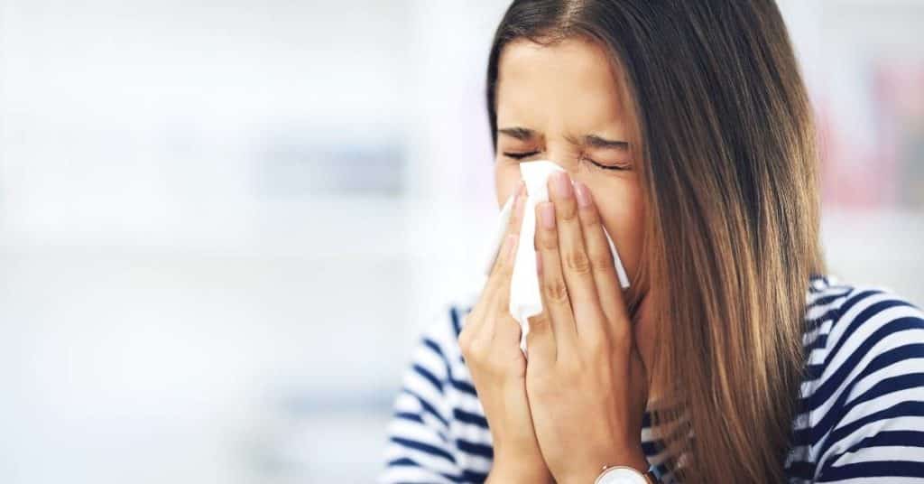 A woman sneezing due to allergies
