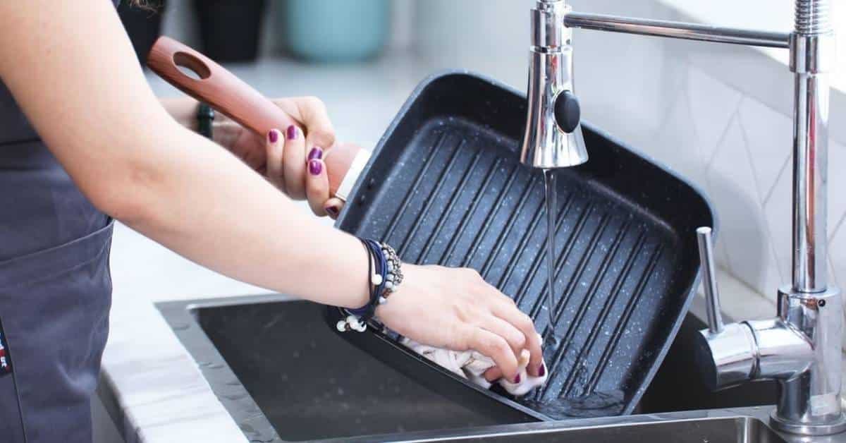 A woman washing a ceramic pan in a sink