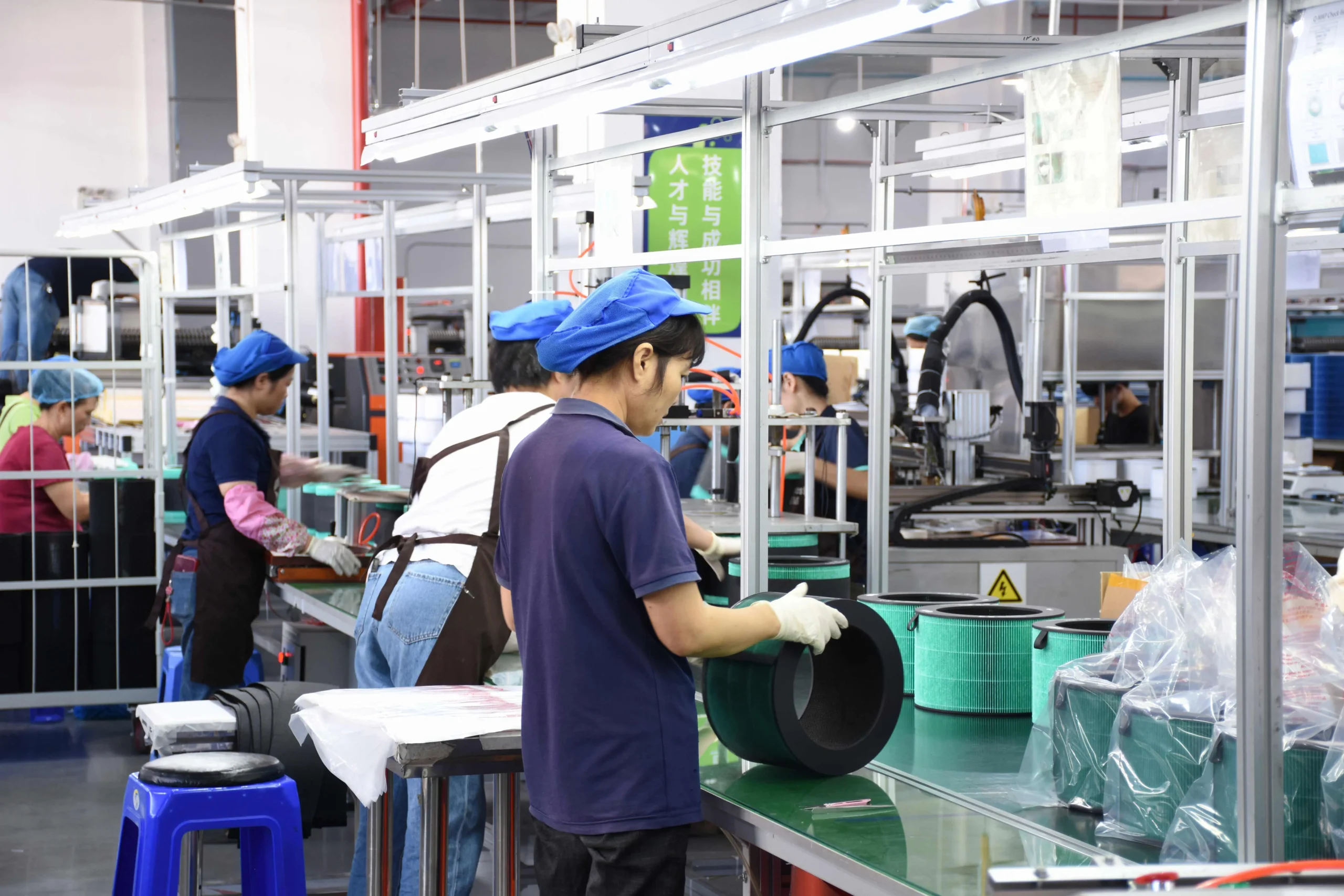 Workers assembling air filters on a production line in a clean workshop.