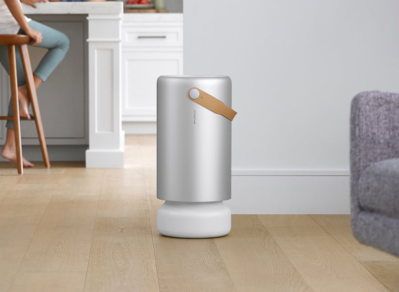 A sleek Molekule air purifier with its distinctive cylindrical shape and leather handle.