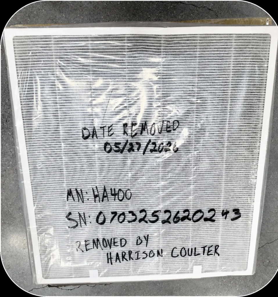 Close-up view of an air filter with written notes indicating removal date, model number (MN: HA400), serial number (SN: 0703252620243), and the name Harrison Coulter.
