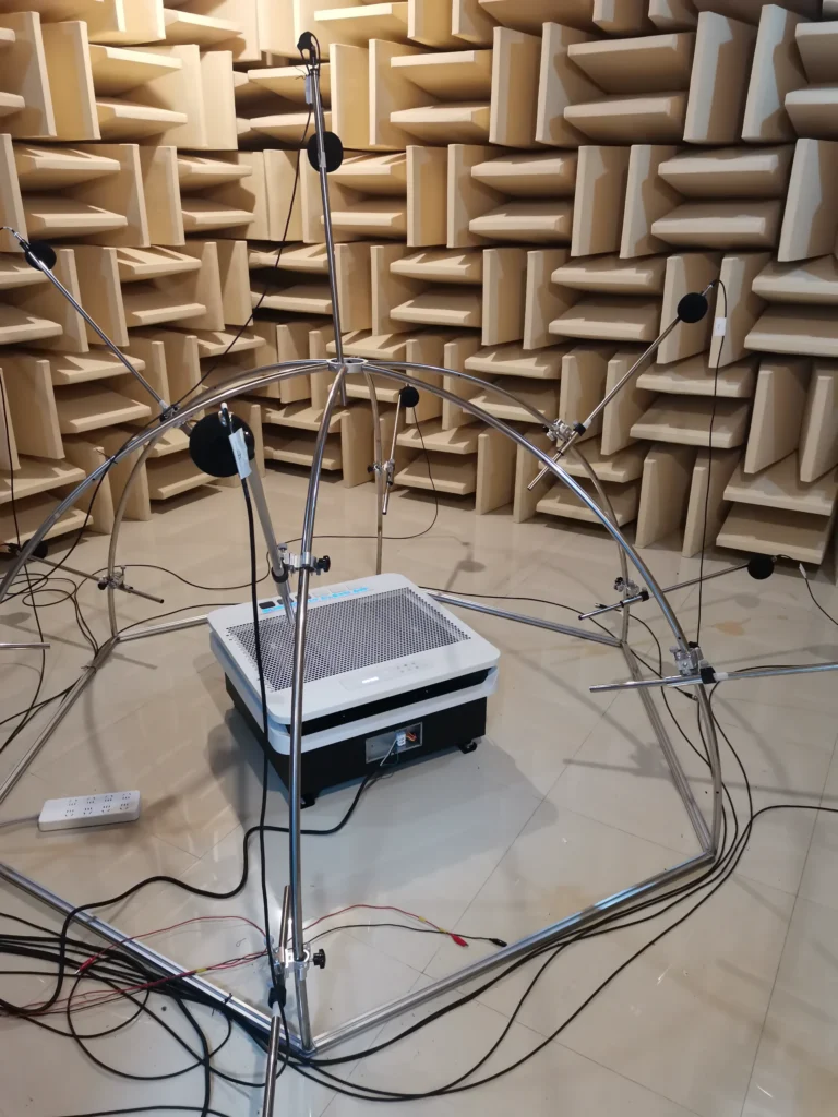 Anechoic chamber with soundproof walls and a setup featuring multiple microphones mounted on a metal frame surrounding a device for acoustic testing.