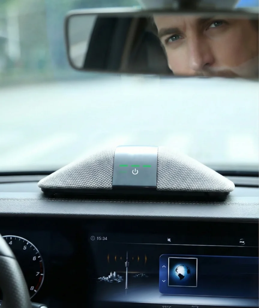 A modern car dashboard featuring a fabric-covered sound system with green and white controls, positioned above a digital display.