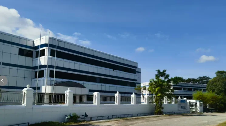 Modern office building with a white facade, large glass windows, and a white fence, set under a clear blue sky.